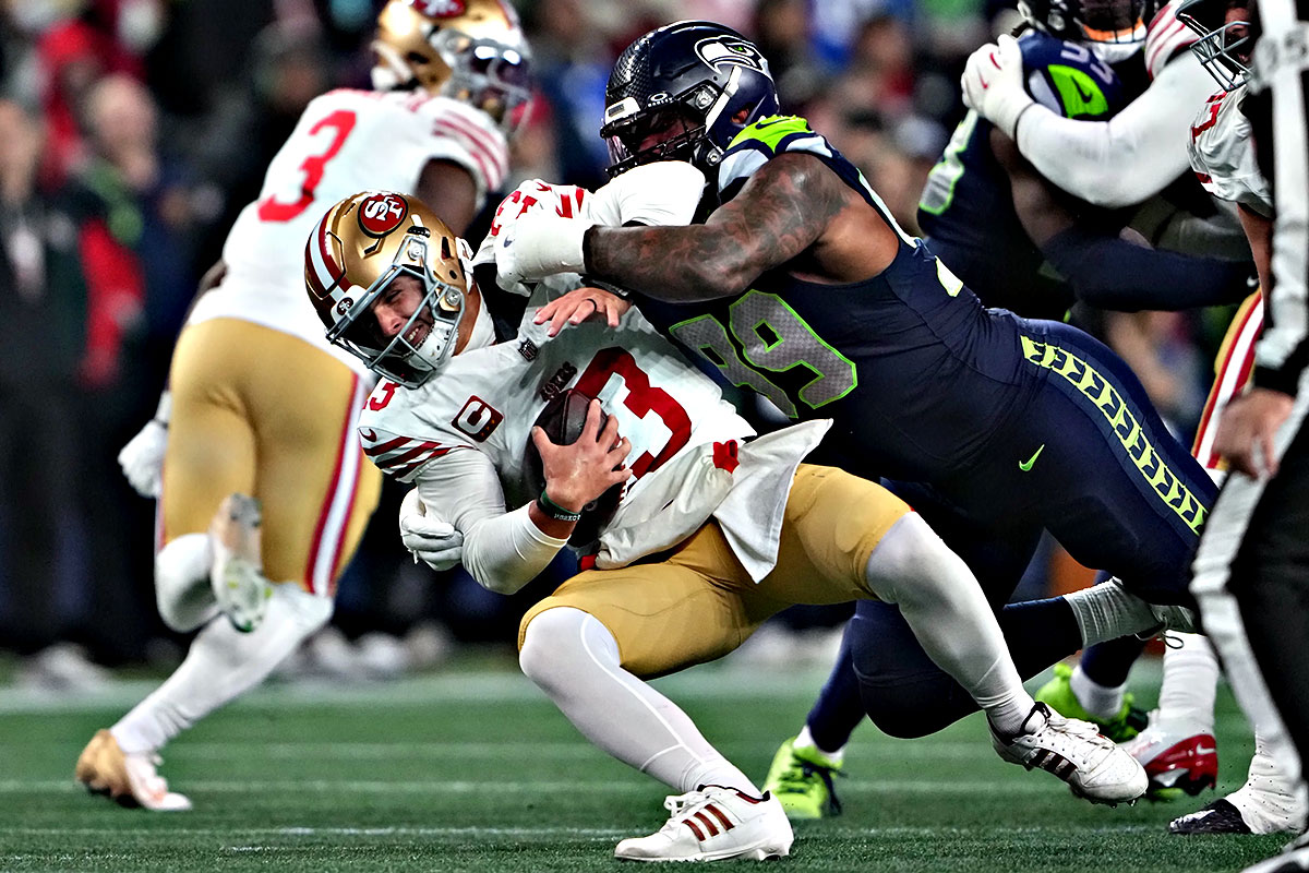Brock Purdy in tasca sotto la pressione della difesa dei Seahawks al Lumen Field